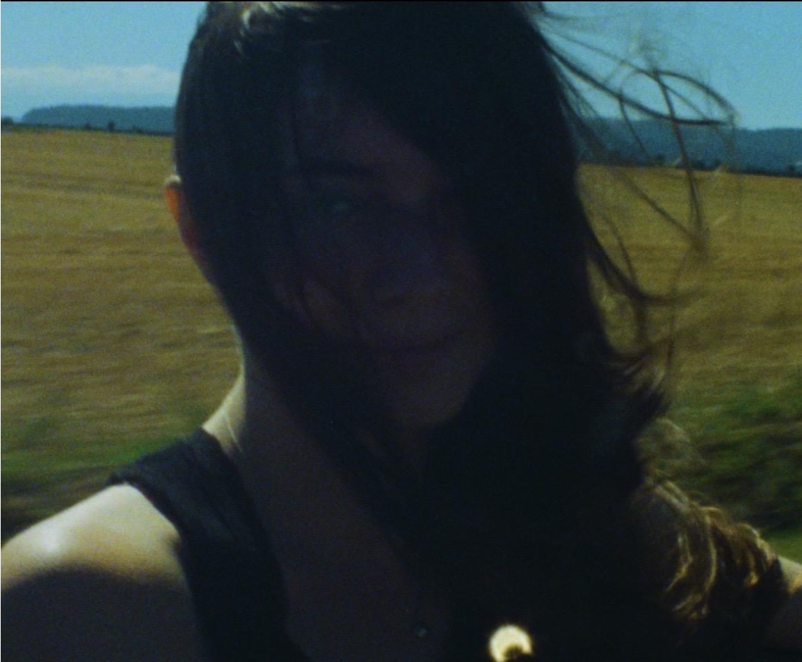 Eliana Glass in a field, hair across her face